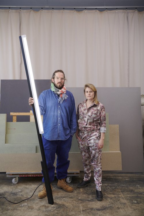 Fabian Jaggi und Katrin Murbach gemeinsam in ihrem Atelier mit Sägespähnen am Boden und angeschnittenen Brettern im Hintergrund