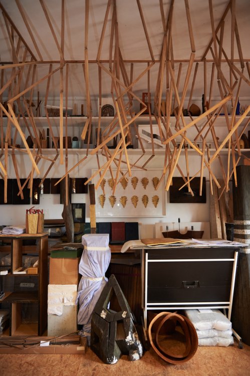 Werkstatt mit hängenden Holzstücken und anderen mehr oder weniger fertigen künstlerischen Arbeiten aus Holz und Gold