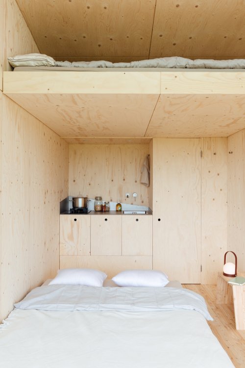 Kleines Holzhaus mit Doppelbett unten und einem weiteren Doppelbett oben auf einem Loft