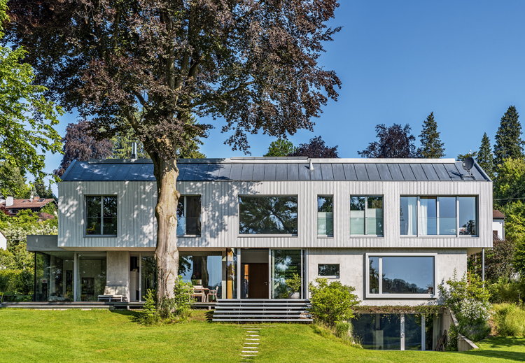 Frontalansicht eines zweistöckigen Einfamilienhauses mit asymmetrischen Satteldach und unterschiedlichen Fensterformaten.