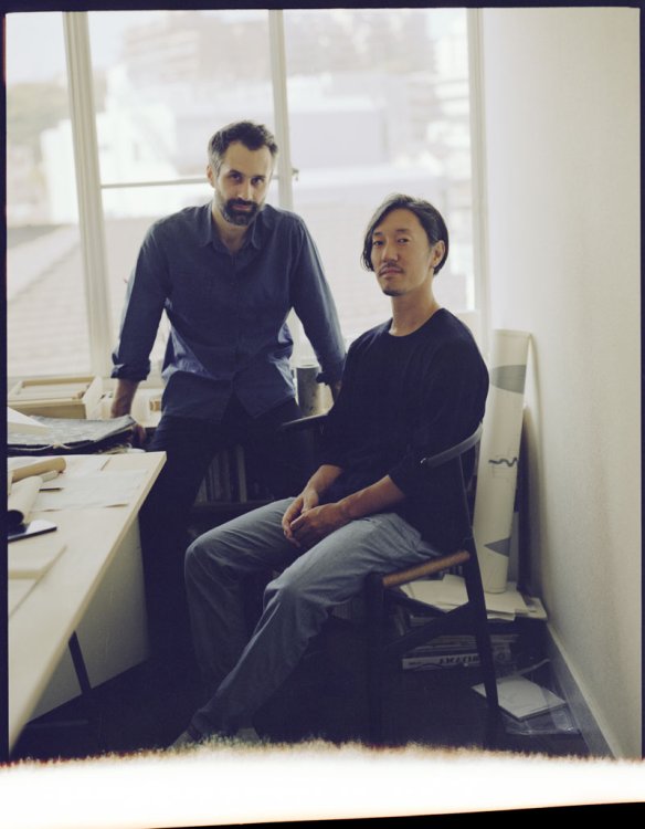 Designer-Duo Mist-o sitzen in einem Atelier und schauen in die Kamera.