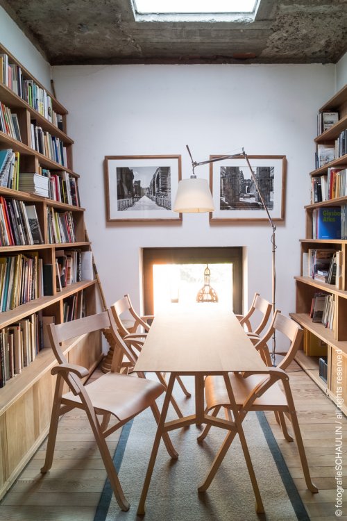 Blick in das Atelier von Michele de Lucchi, seitliche Bücherregale und Holztisch mit vier Stühlen in der Mitte.
