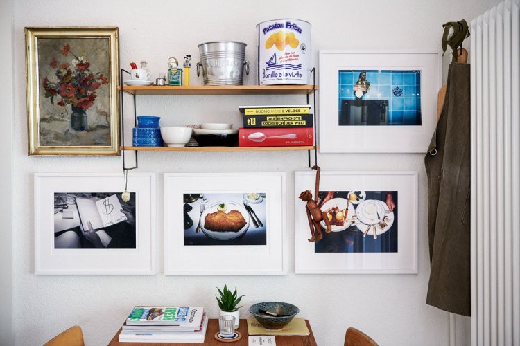 Küchenwand ob Tisch mit Bildern und Regal mit Küchenuntensilien.
