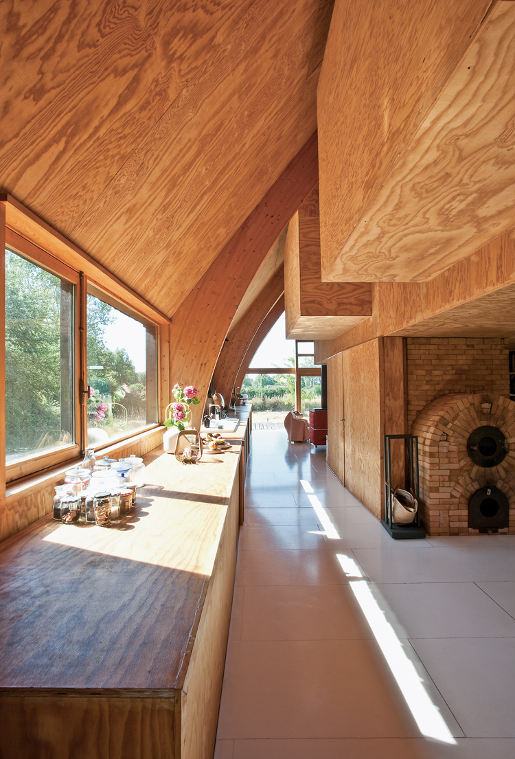 Durchblick in einem Holzhaus mit Fensterfront auf der linken Seite und Wohnzimmer in der Front.