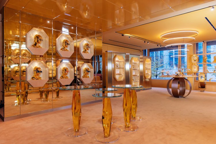 Monochrom in Gold gehüllter Laden vom Teppich über Wände mit Spiegelelementen bis zu den Decken und einem Präsentiertisch mit goldenen Beinen.