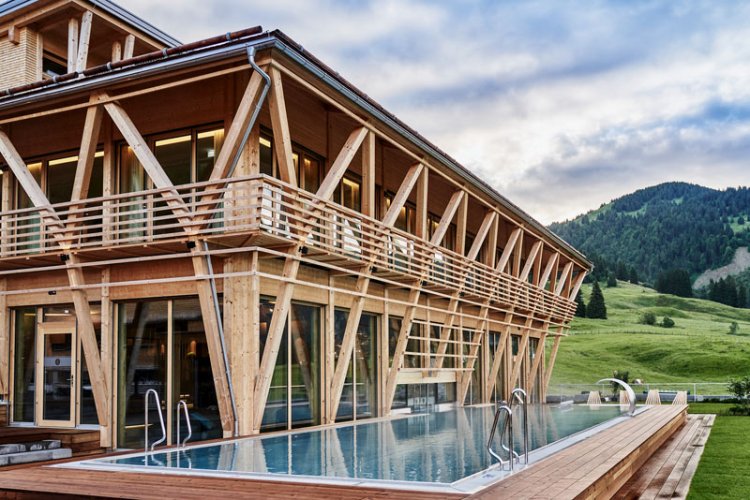 Aussenansicht modernes Holzgebäude in der Natur mit auffälliger Balkenstruktur und Pool.