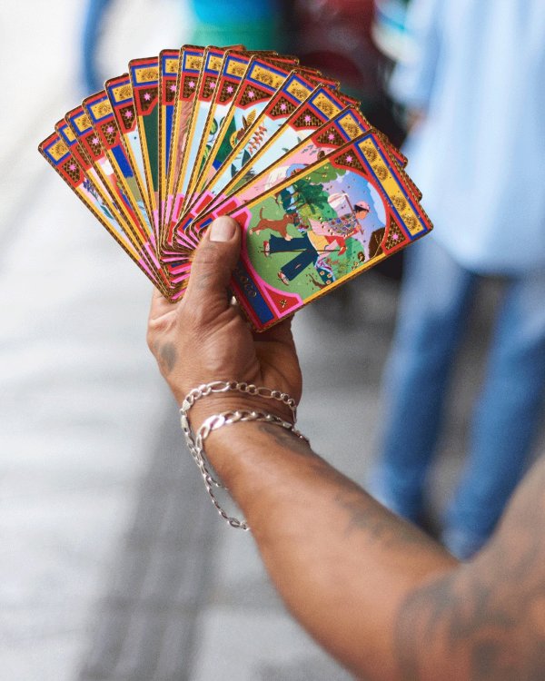 Eine Männerhand mit Tattoos und dem ausgefächerten Tarot-Karten-Set von Tauta.