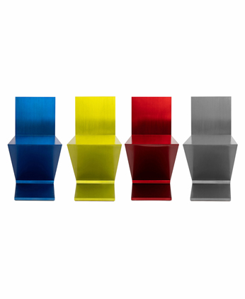 Der Zig Zag Stuhl von Gerrit T. Rietveld in vierfacher Ausführung aneinandergereiht in den Farben Blau, Gelb, Rot und Grau.