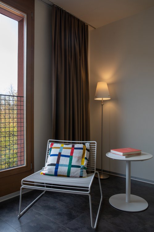 Sessel mit Kissen und einem kleinen runden Beistelltisch in einem modernen Schlafzimmer.