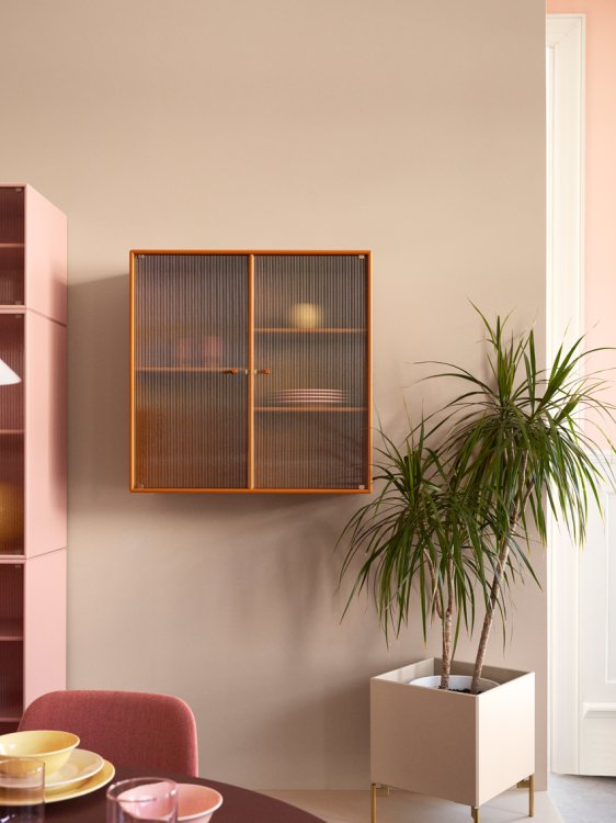 Neuer Vitrinenschrank von Monatna Furniture in rosa vor gelber Wand.