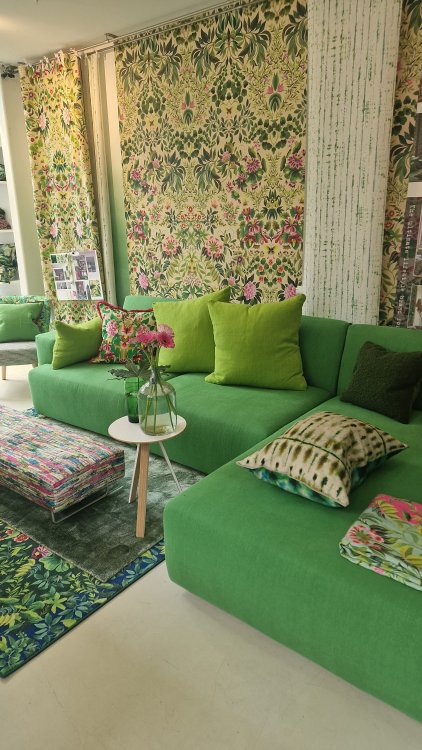 Grünes Sofa mit floraler Tapete ebenfalls in grün-pink-Farbabstufungen.