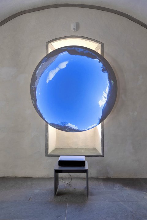 Ausstellungsansicht der Ausstellung HEMAUER/KELLER — Über den menschgemachten Himmel im Nidwaldner Museum zeigt eine übergrosse blaue Glaskugel vor einem Fenster des Ausstellungssaals.