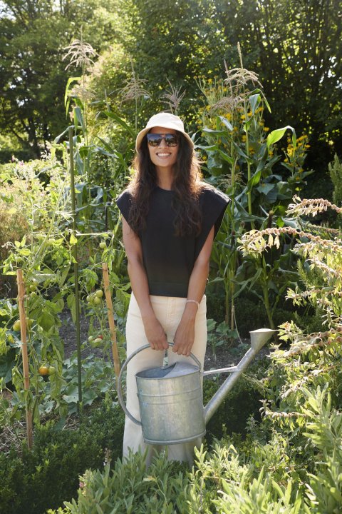 Karen Fleischmann steht in einem Garten mit Giesskanne in der Hand