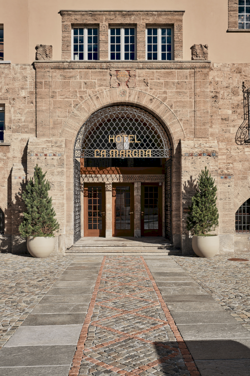 Ursprünglicher Hoteleingang mit altem Schmiedeeisen-Schriftzug La Margna und Türeinfassung aus Tuffstein mit schlichten Dekoren.