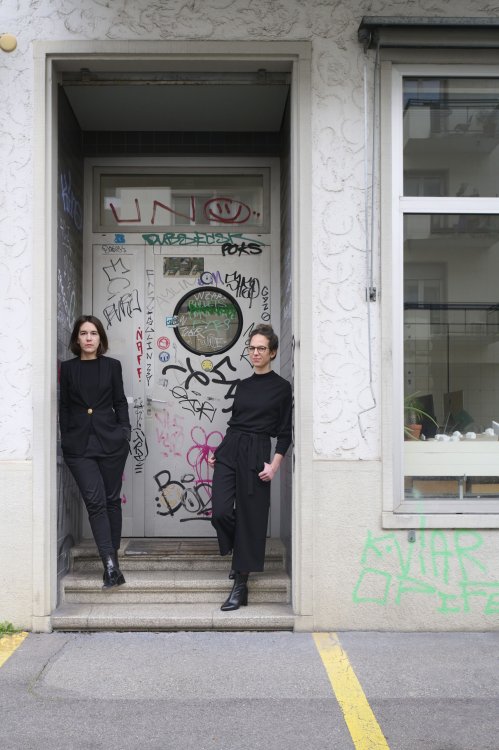 Die zwei Architektinnen Anouk Schepens (steht links) und Nicole Würth stehen vor dem Eingang ihres Büros im Kreis 4. Auf der Tür sind Graffitis und Kritzeleien zu sehen.