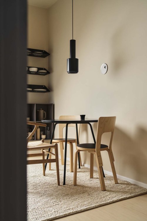 Ein Foto eines kleinen schwarzen, runden Tisch der von drei Stühlen umgeben ist und in der Küche steht.