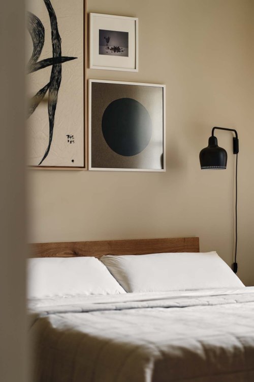 Ein Foto eines Ausschnittes des Schlafzimmers. Man sieht das Bett ein wenig, über welchem zwei eingerahmte Bilder stehen.