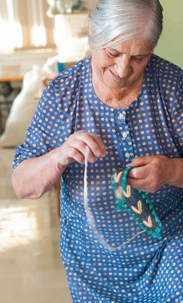 Eine alte, griechische Dame die von Hand Hausschuhe strickt.