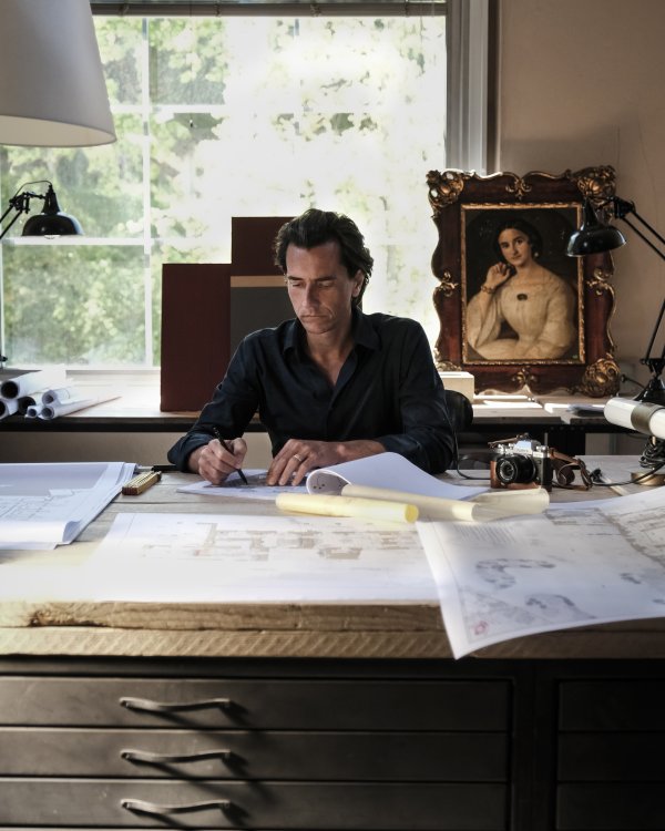 Besitzer Benedikt Bolza der an seinem Schreibtisch sitzt und von Zeichnungen und Plänen umgeben ist.