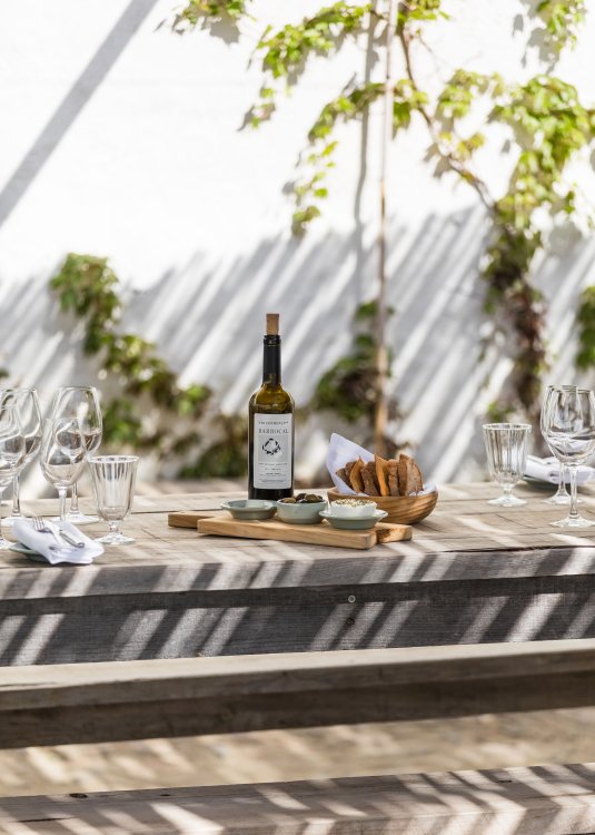 Ansicht eines Tischs auf dem diverse Rot- und Weissweinflaschen des Hoteleigenen Weins aus dem São Lourenço do Barrocal platziert sind.