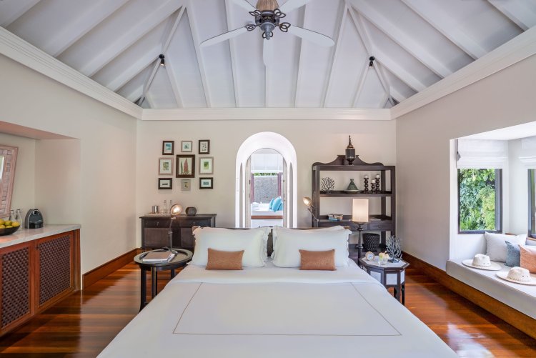 Das Schlafzimmer in einer der «Familiy Beach Pool Villen» mit hohem Spitzdach ist in weiss und dunklen Holztönen gestaltet und versprüht ein Mix aus Motiven des Indischen Ozeans, aus Arabien und Portugal.