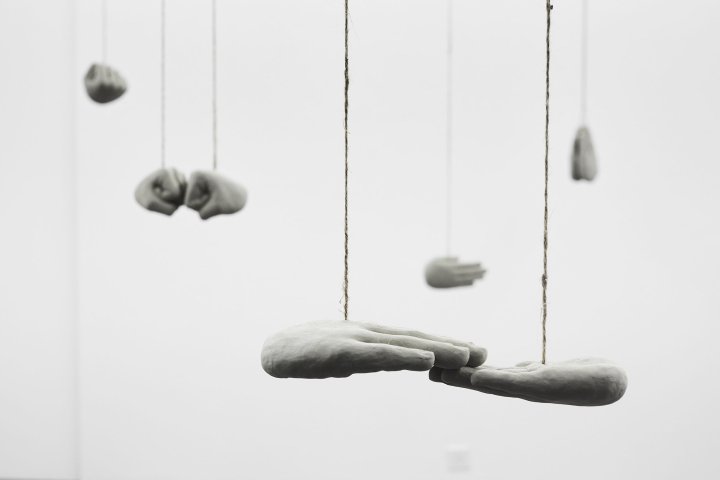 Eine Kunstinstallation der Ausstellung "Art as Connection" zeigt je zwei Paar von der Decke hängende Hände aus Beton, die sich berühren.