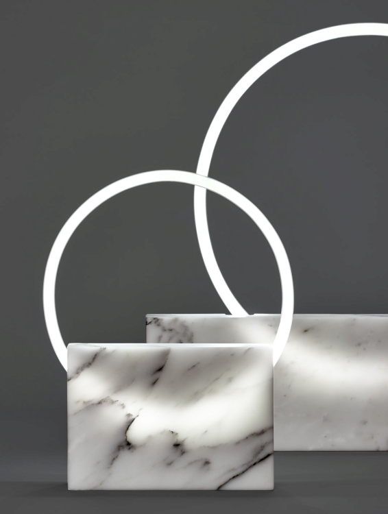 Zwei Lampenobjekte von Bloc Studios in Zusammenarbeit mit Sabine Marcelis bestehend aus einem rechteckigen Marmorsockel und einem kreisrunden Leuchtrings welcher vor dem Marmor angebracht ist.