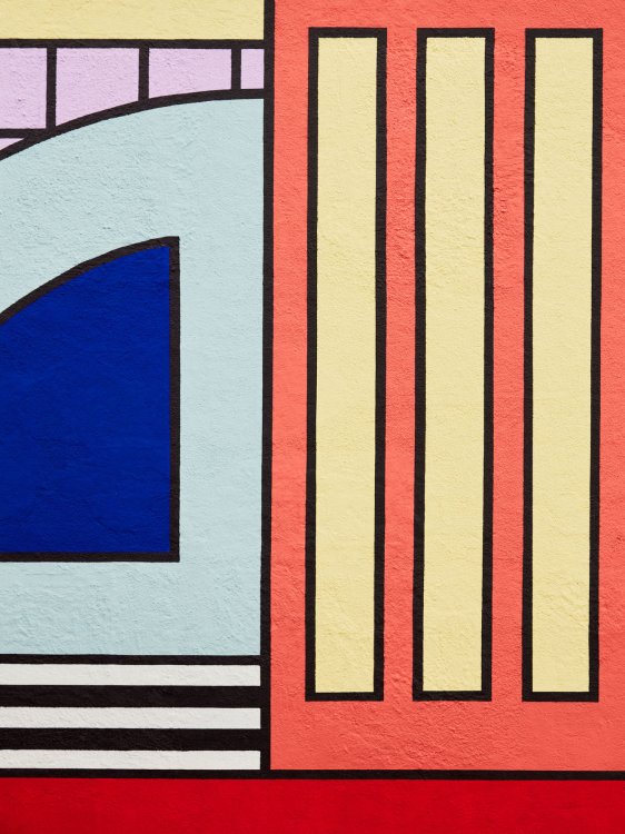Nahaufnahme der farbigen Fassadengestaltung der Montana-Fabrik mit geometrischen Formen in knalligen Farben und schwarzen Linien.