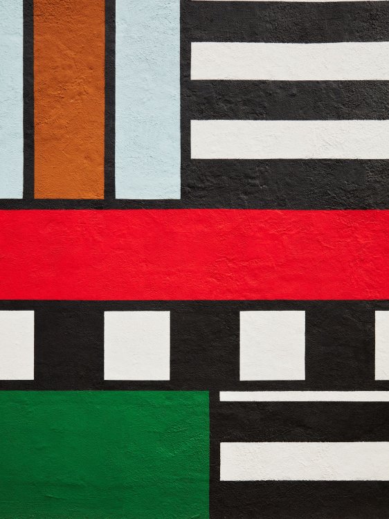 Weitere Nahaufnahme der farbigen Fassadengestaltung der Montana-Fabrik mit geometrischen Formen in knalligen Farben und schwarzen Linien.