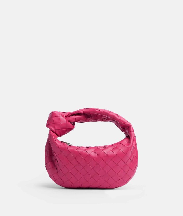 Eine pinke Mini-Handtasche mit einem Knoten im Henkel und Flechtlederoptik in sattem Pink.