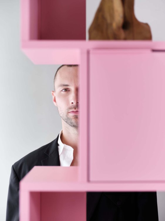 Der Digitalkünstler Andrés Reisinger steht hinter seinem mit Tylko entworfenen Regal in Pink und blickt in die Kamera.