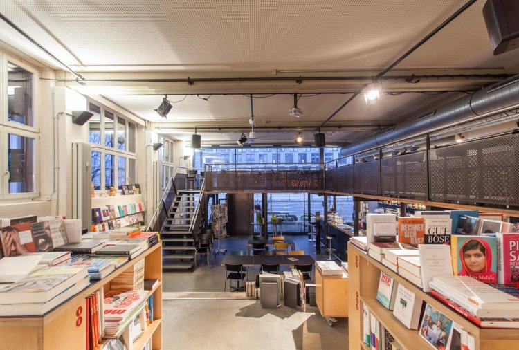 Blick zwischen den Bücherregalen zur Fensterfront und ins Café Sphères